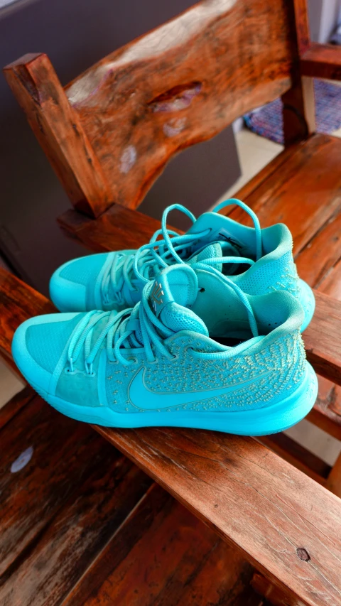 blue sneakers with sparkly accents sit on a wooden bench