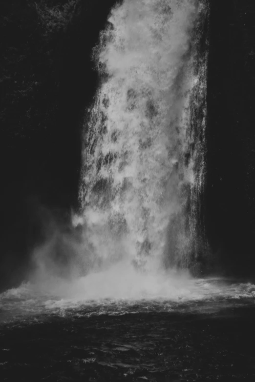 a waterfall with water pouring from it into the dark