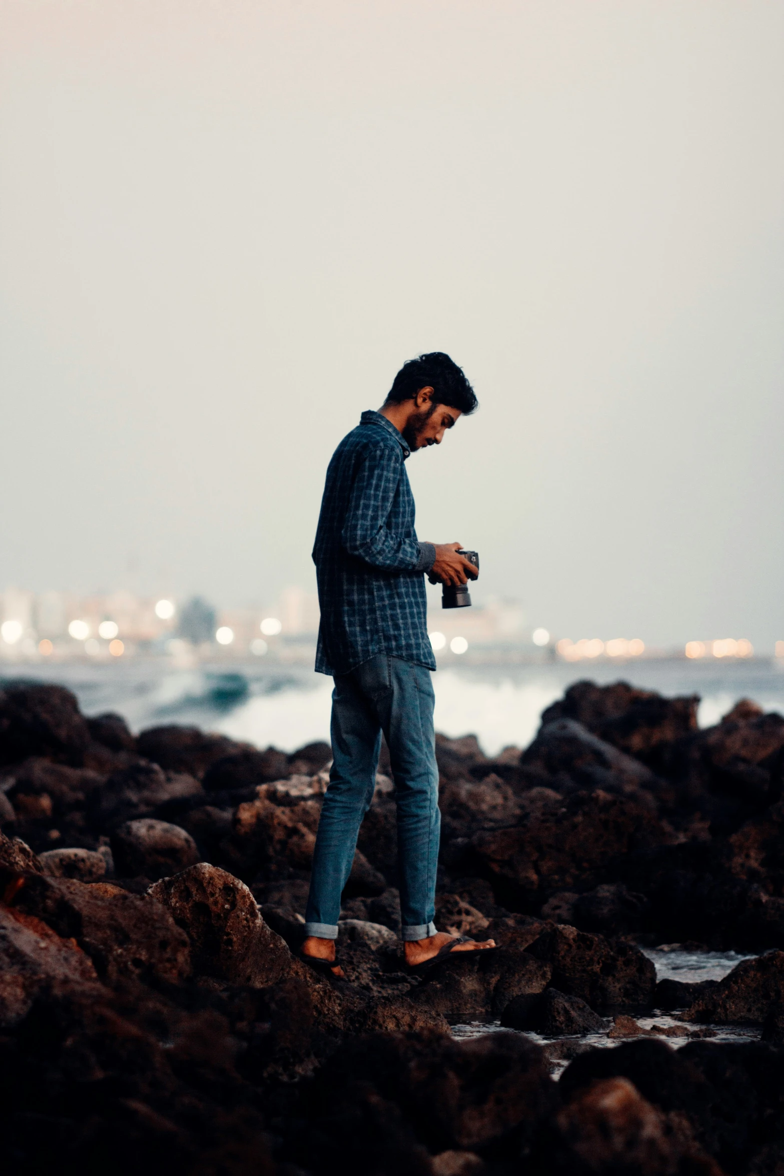 a man looks down at his cell phone in a rocky area