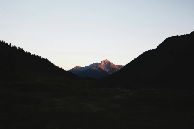 a mountain range in the distance with a sun setting