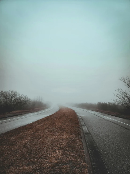 a road surrounded by fog on the side of it