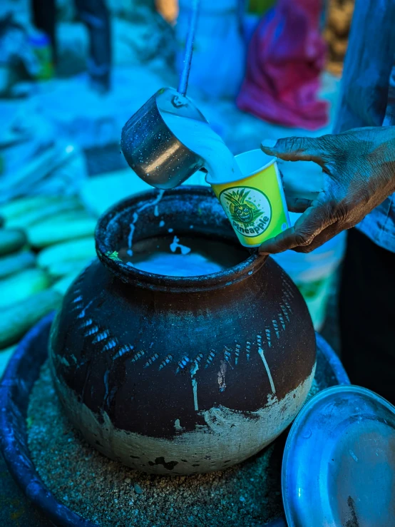a person pours liquid from a pitcher into an earthen bowl
