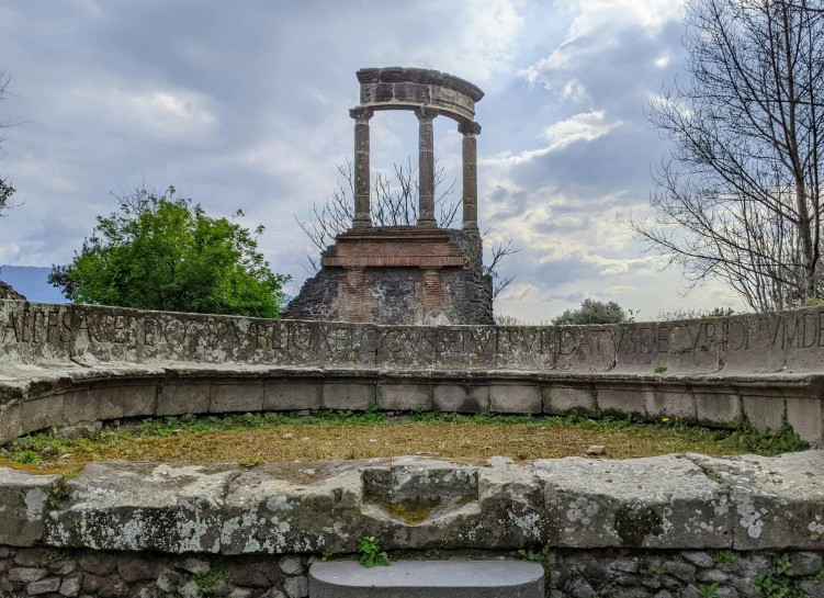 a stone circular structure surrounded by greenery