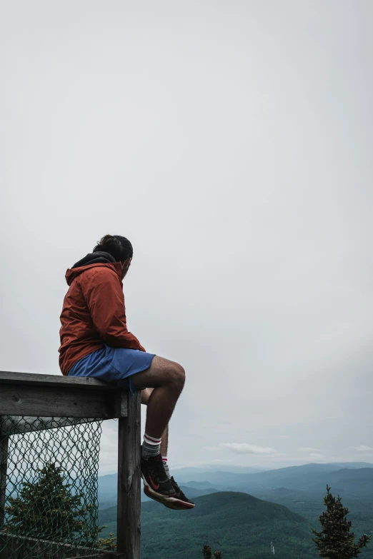 a man sitting on top of a wooden fence