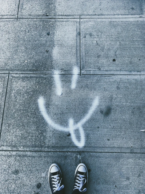 a person standing on sidewalk that has drawn shoes