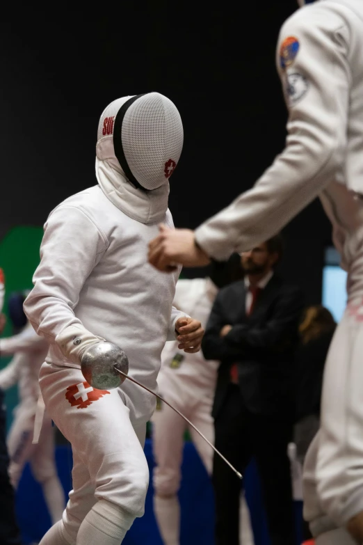 the athletes are engaged in fencing as one holds his hands out with a fist