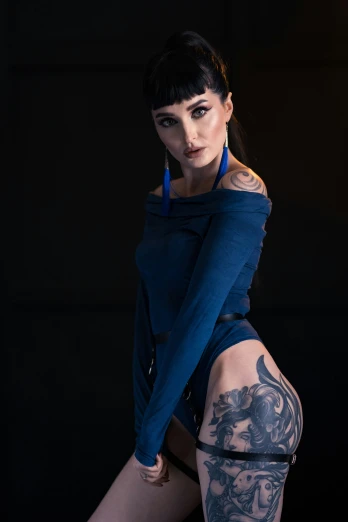 a young woman with dark hair and tattoos poses