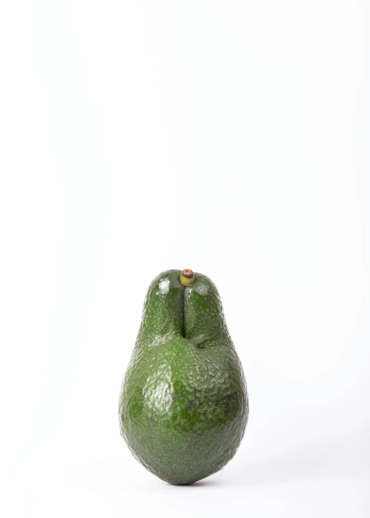 there is a green avocado sitting up on the counter