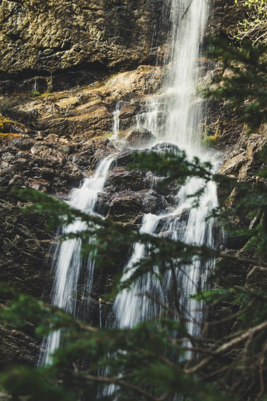 a waterfall and pine trees in the mountains