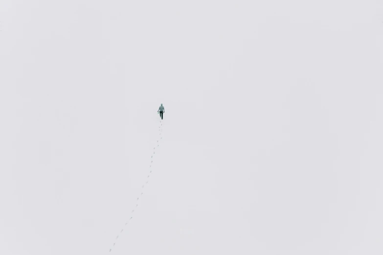 a person standing on a snow covered hill flying a kite