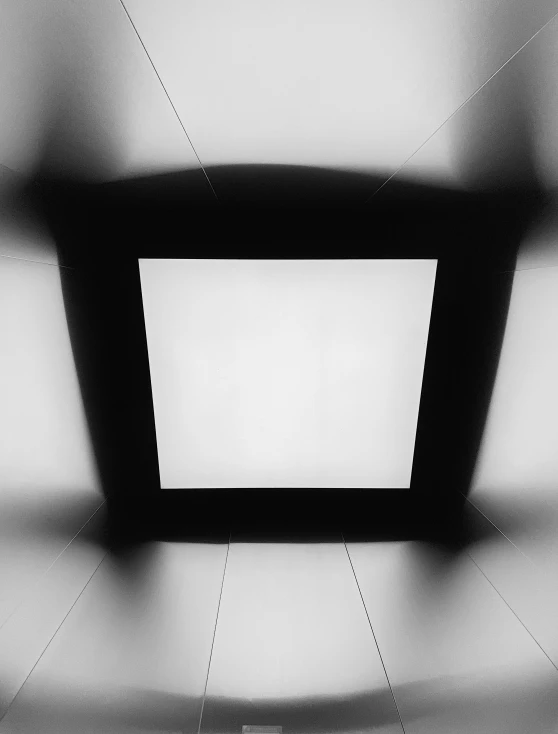 a black and white po of a square ceiling with light shining from the bottom