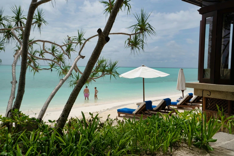 several lounge chairs under umbrellas on a tropical beach