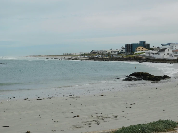 a body of water sitting next to a beach with some buildings