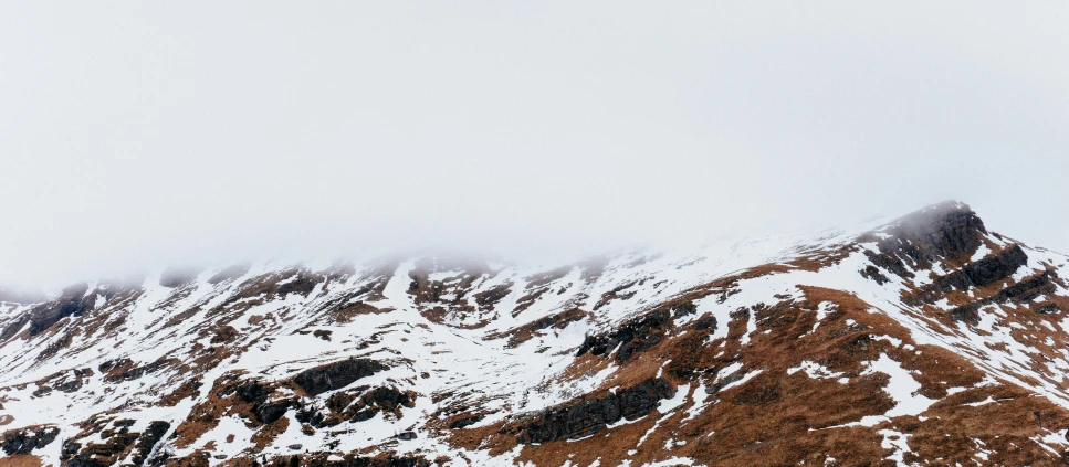 a very tall snowy mountain in a cloudy sky