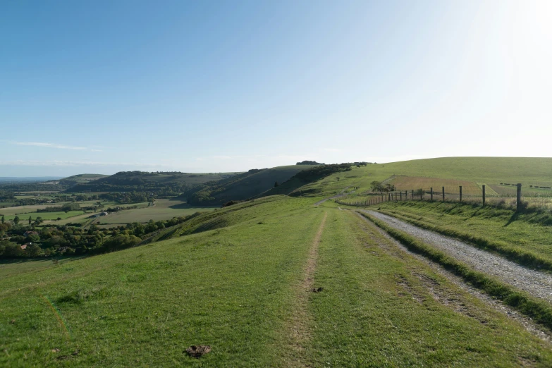 the sun shines on a very green hill