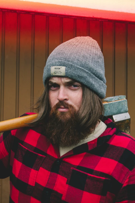 a man with a long beard and a knit cap, holding an ax