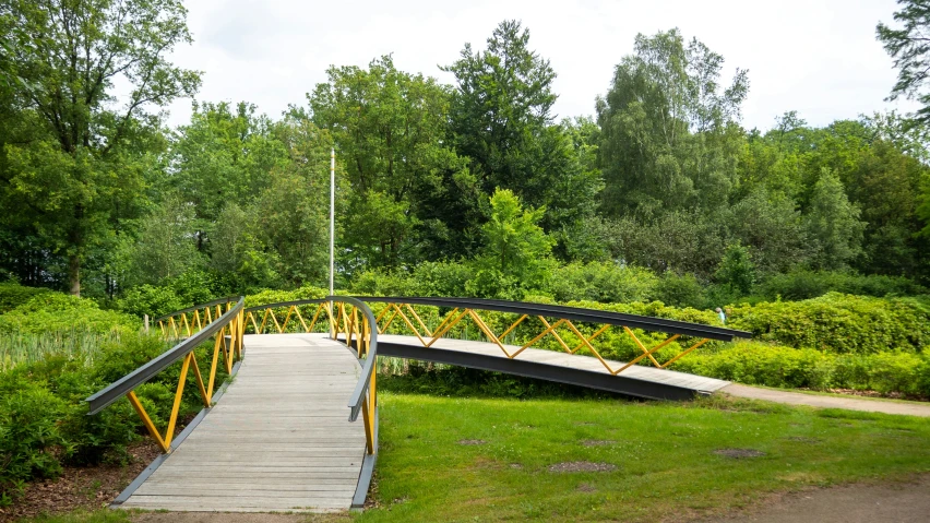 a wooden bridge crossing over a green field