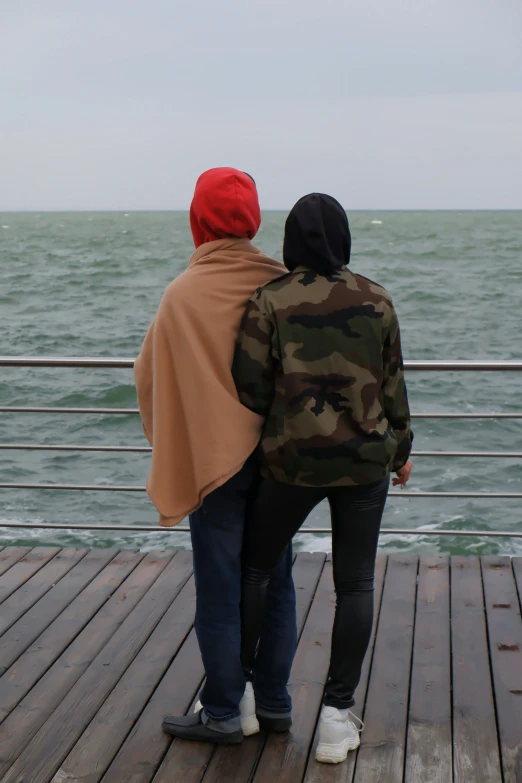 a couple looking out over the ocean from a pier