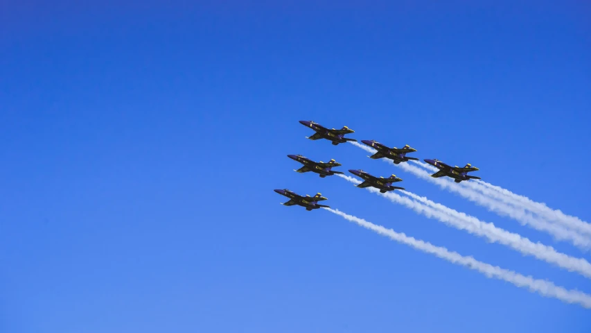 four jets fly through the air, leaving a long trail of smoke