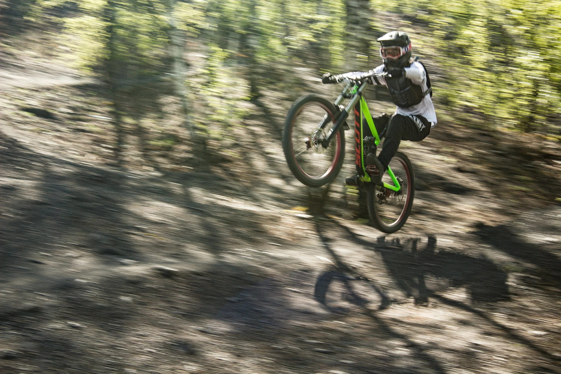 a mountain biker riding down a trail through trees