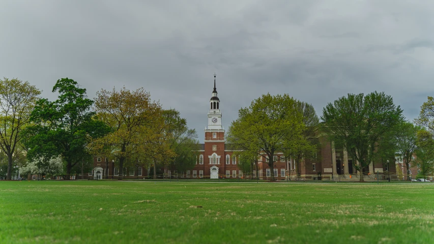 a large brick building with a clock tower sitting in the middle of a field