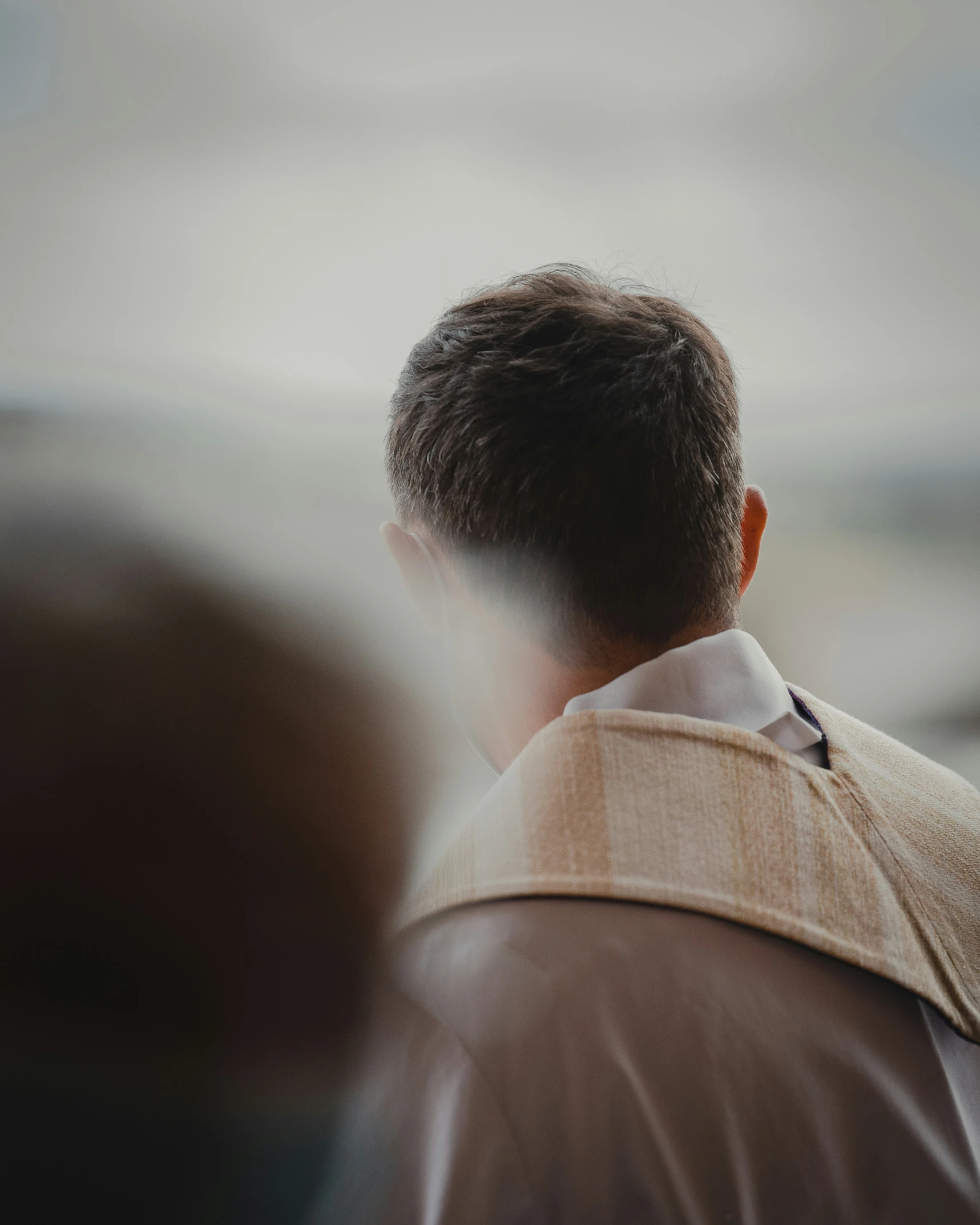 a man with back to the camera looking out at some hills