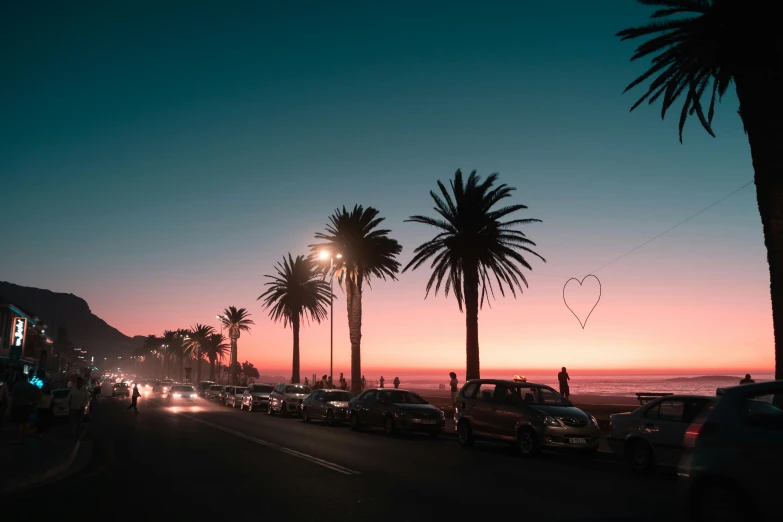 cars are parked on a street near the ocean