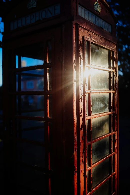 an old red telephone booth stands in the light