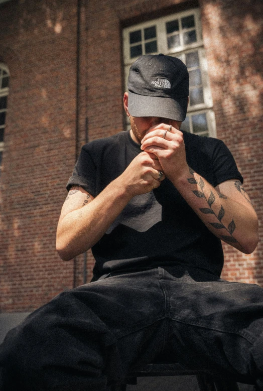 a man sitting outside and praying with his hands folded over his face