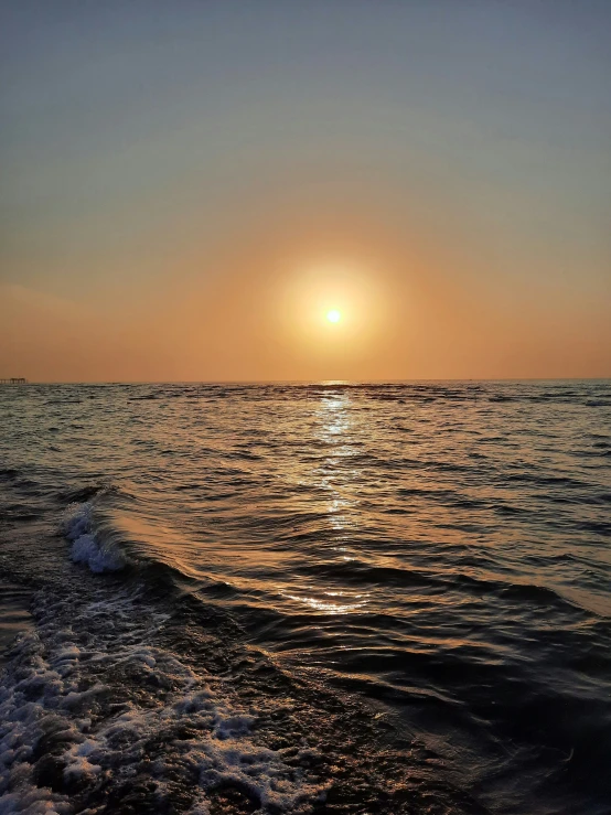 the sun rises over a body of water near the beach