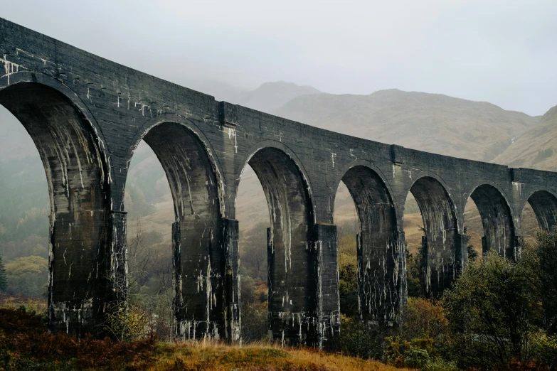 an old, dark colored train with arched arches