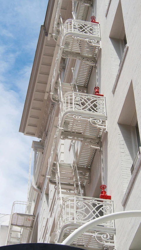 a tall building with red and white fire escape stairs on the top floor