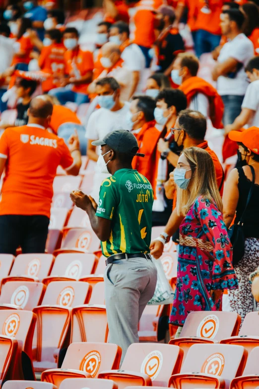 many fans are sitting on the stands in an orange stadium