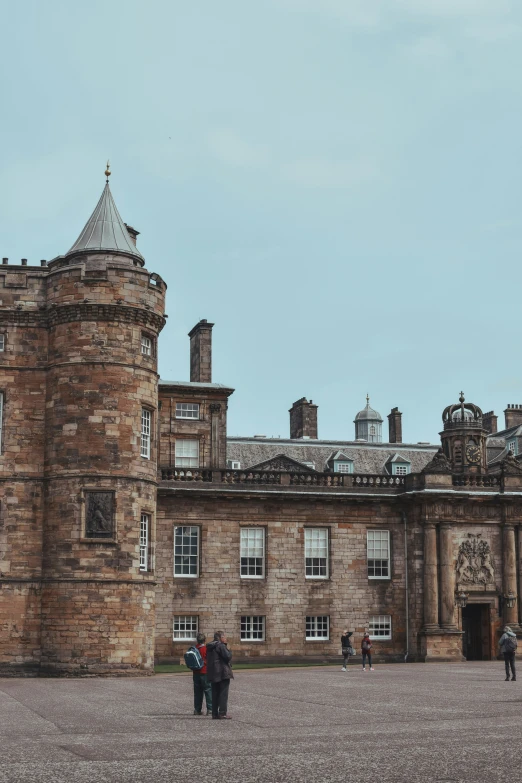 people stand outside an old castle like building