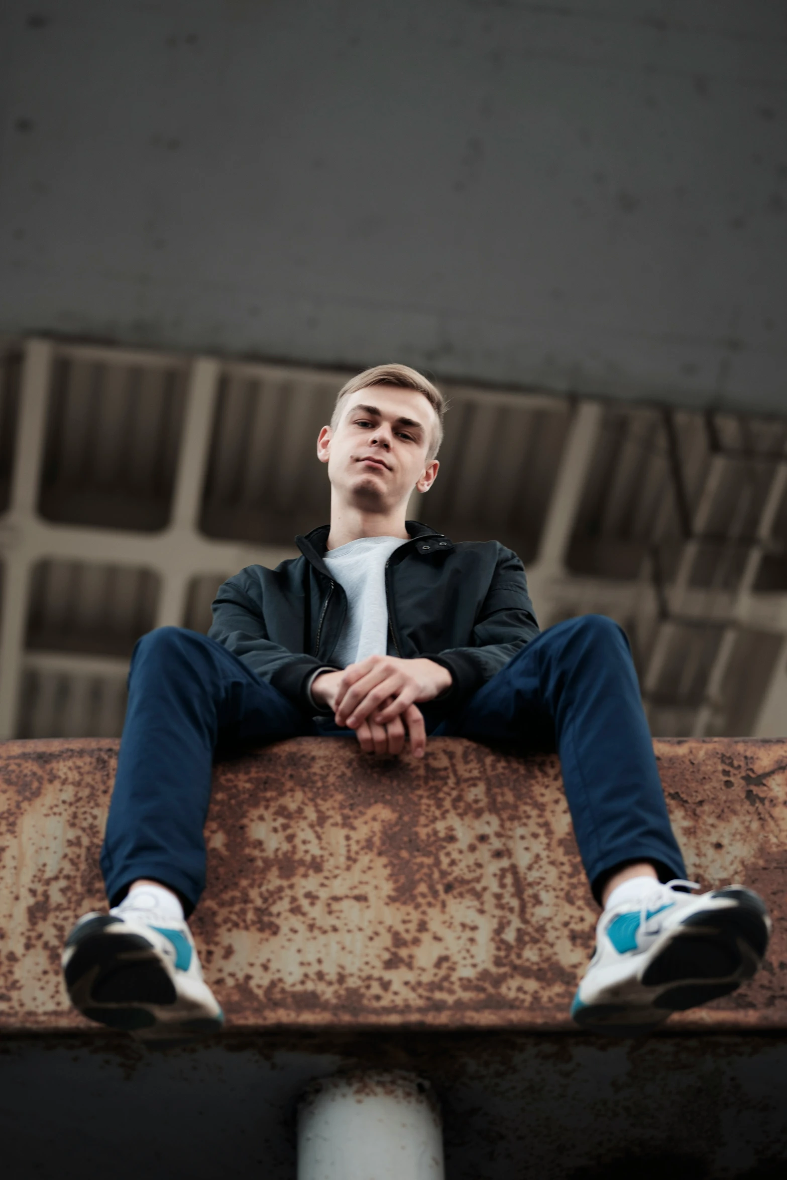 the man is sitting down on top of a rusted metal ledge