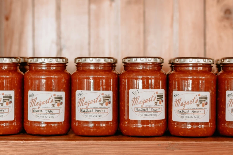 six jars of spaghetti sauce sitting on top of a wooden shelf