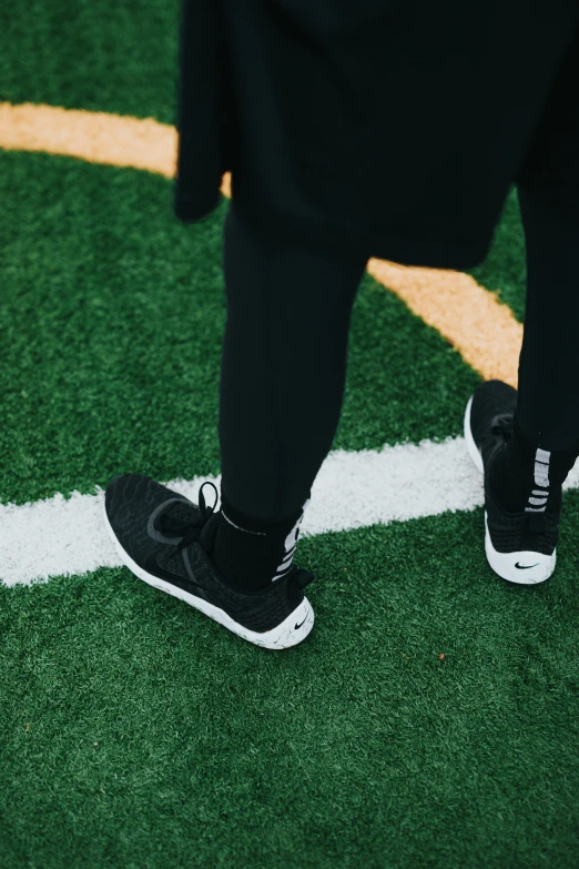 a man standing on a field wearing black and white shoes