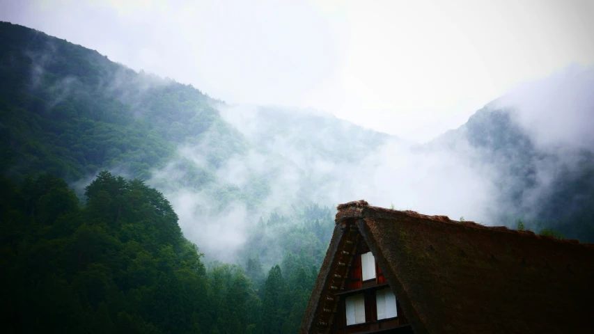 a building with a roof, and mountains in the background