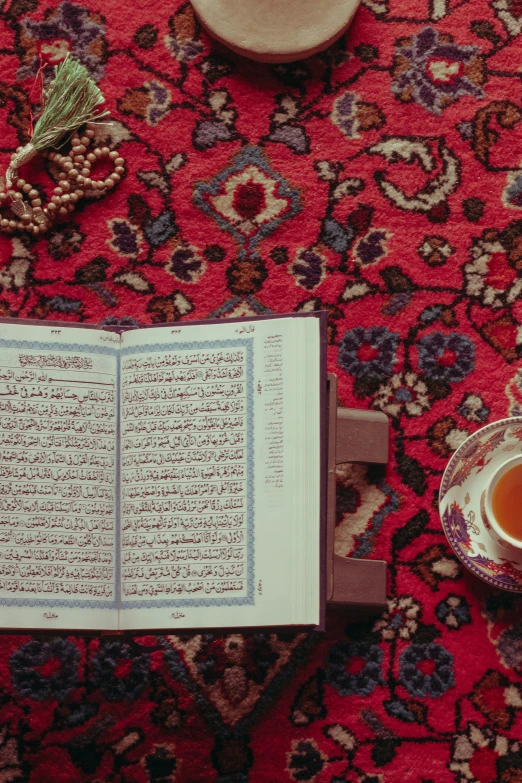 a coffee mug and book on a rug with rosary beads