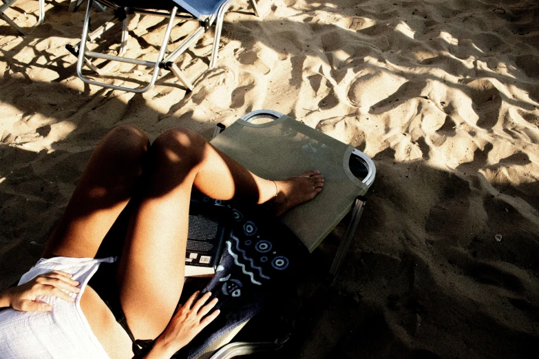 a person sitting in the sand using a computer