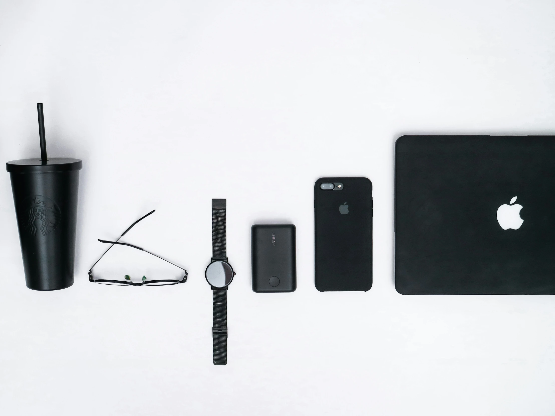 a white surface has an apple logo and phone, accessories