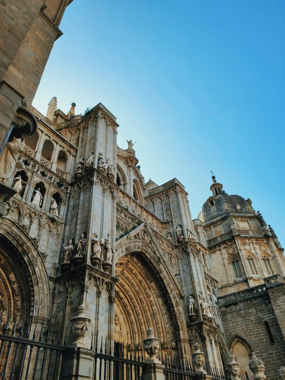 an ornate cathedral with a stone fence in the foreground