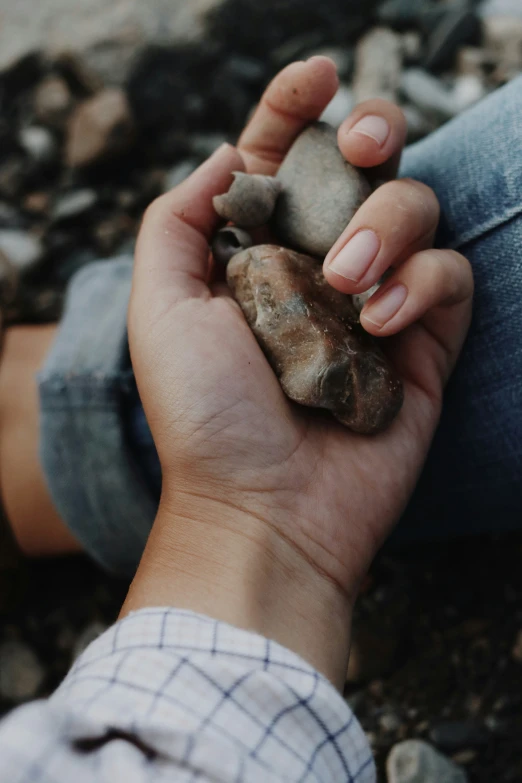 a person's hands holding a rock in the middle of rocks
