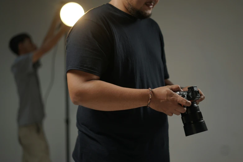 man in black shirt and camera and another person with one hand raised