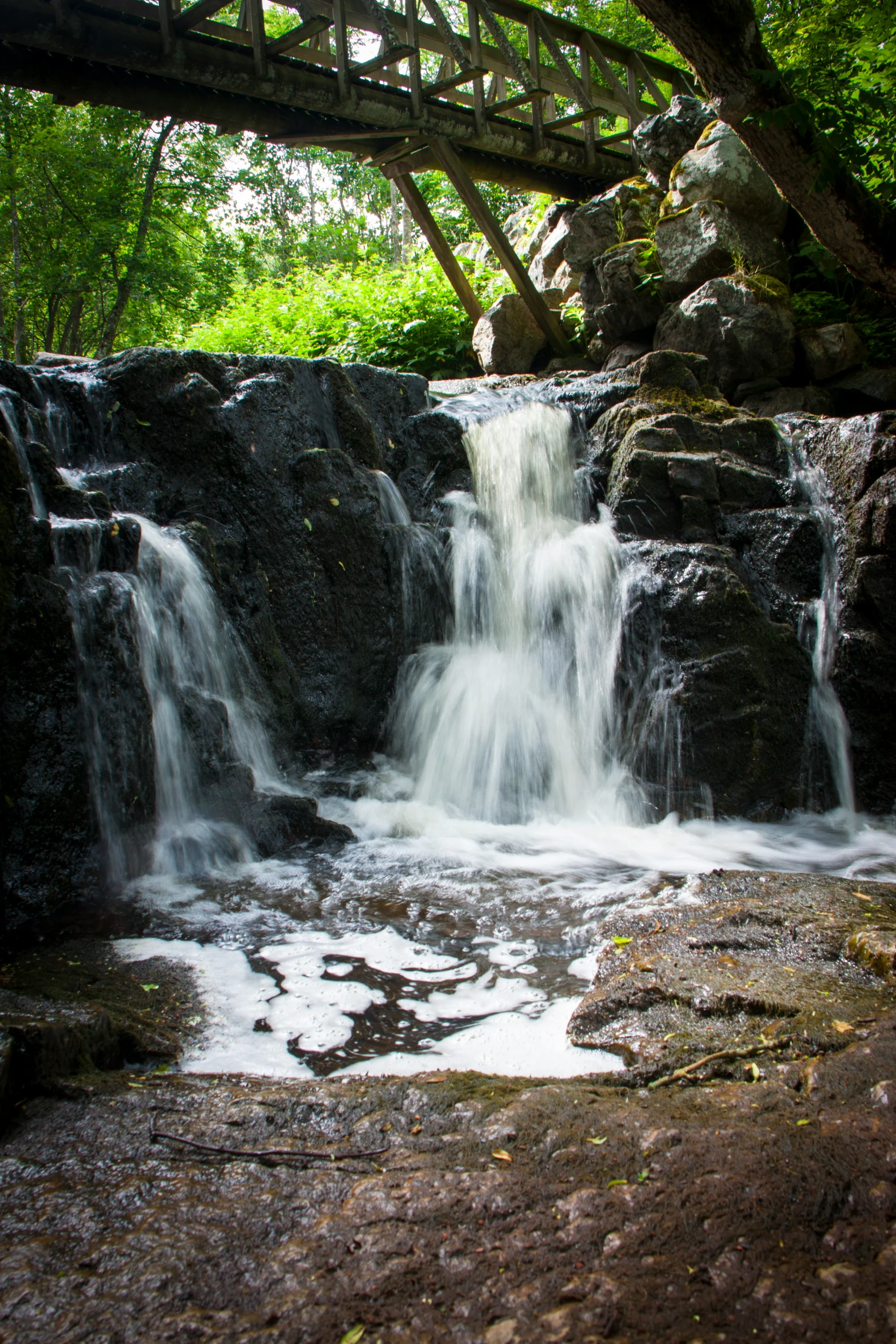 water fall under a bridge with a sky blue sky