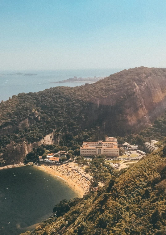 a long, green hill with an ocean and mountains in the background