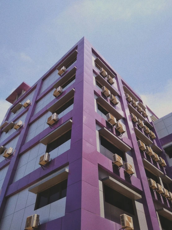 a tall purple building has a balcony