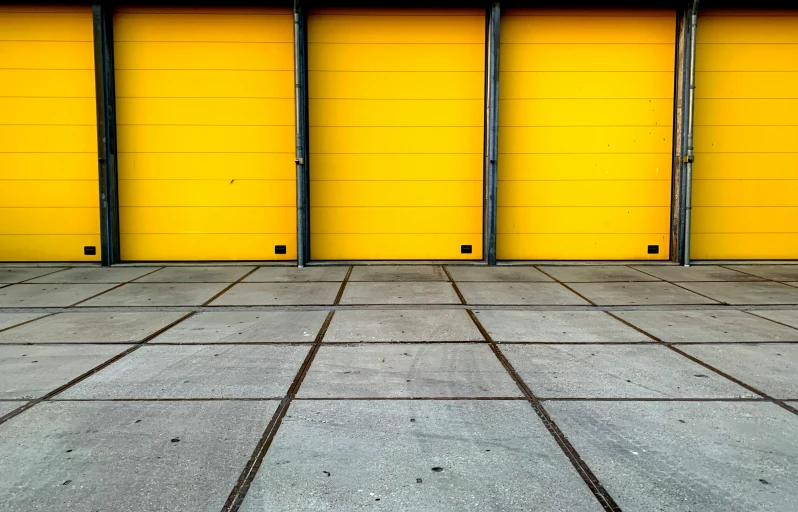 a yellow building with a row of closed garage doors