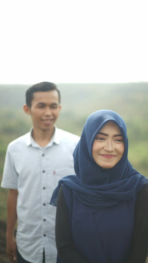 a man and woman stand smiling at the camera