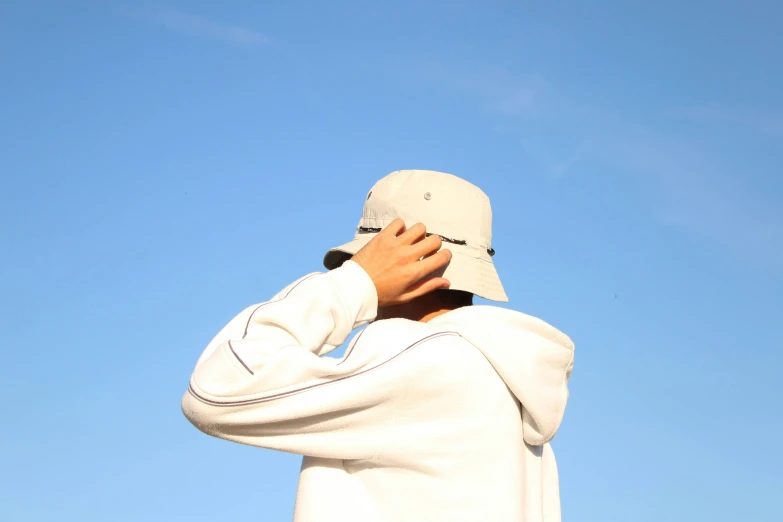 the back view of a man in white sweatshirt and a hat covering his face